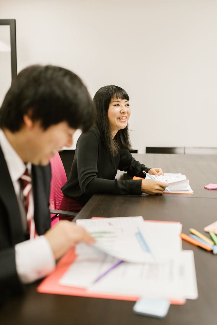 pexels photo 7845333 A businesswoman smiling during a meeting alongside colleagues in an office setting.