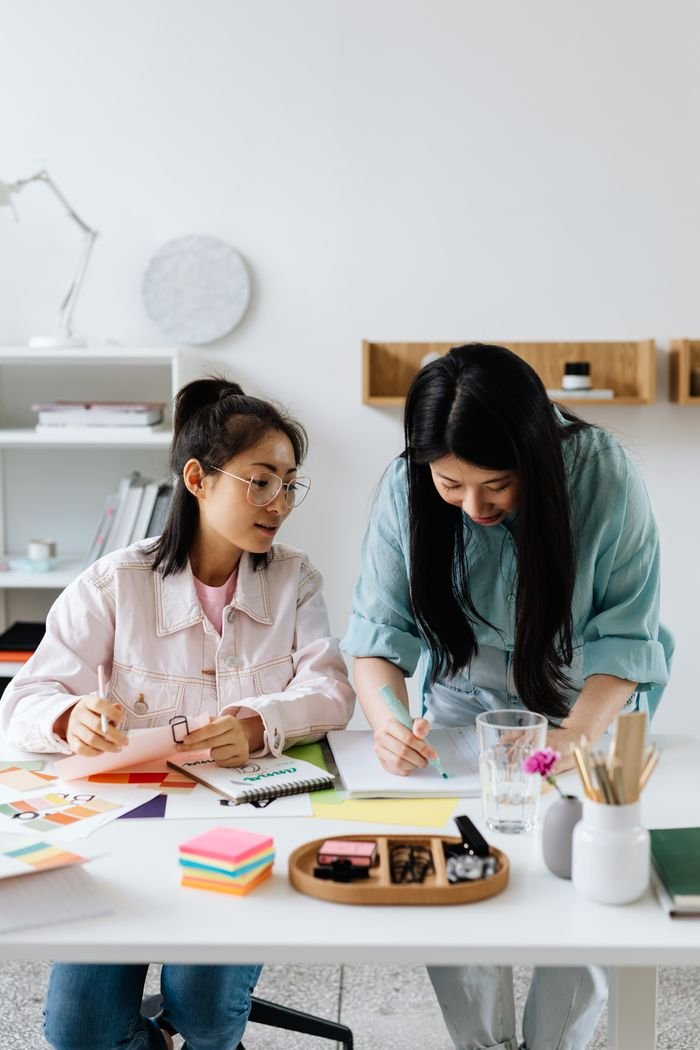 pexels photo 8546550 Two Asian women working together at a desk in a bright, modern office space.